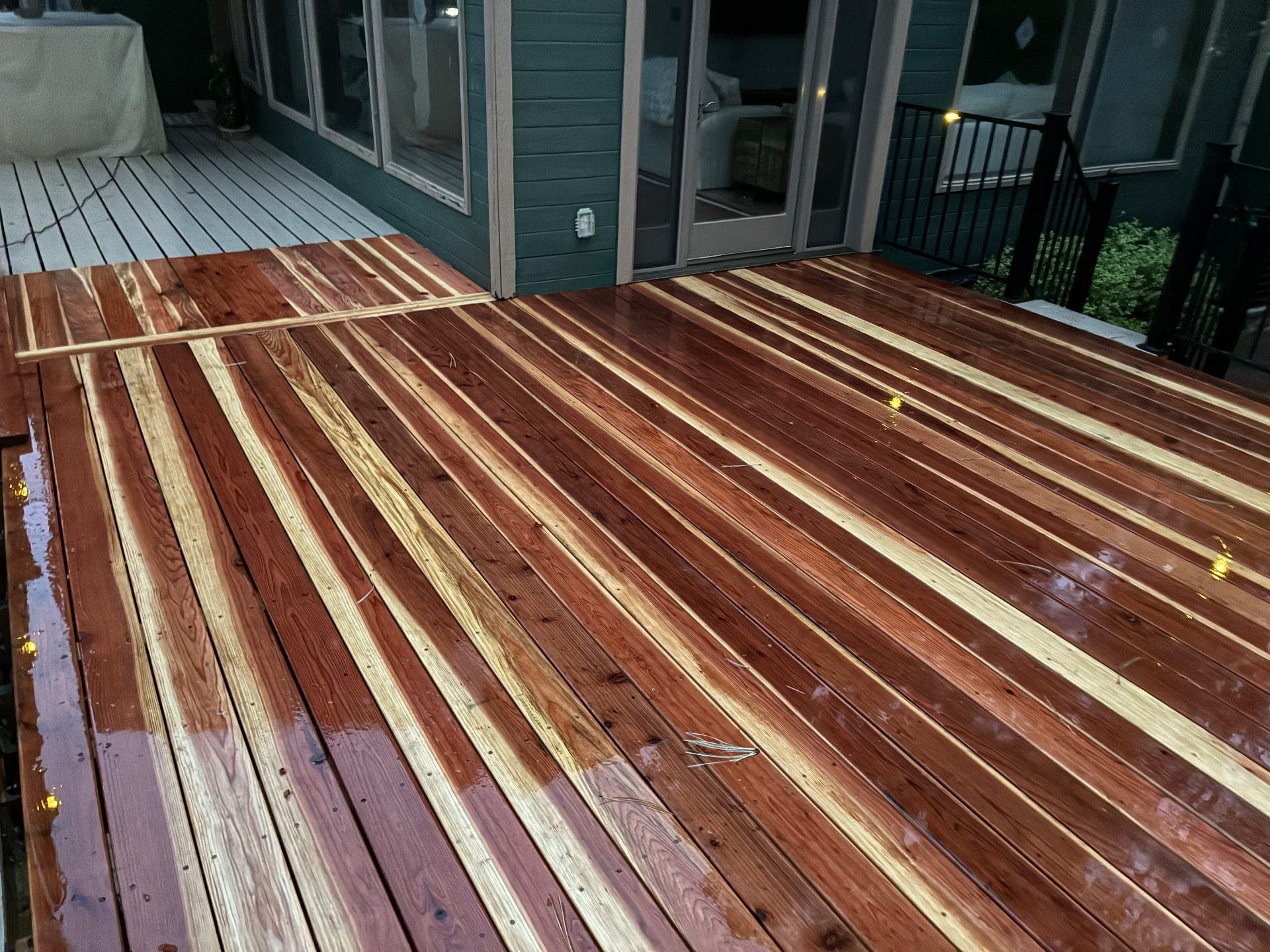 Stained cedar deck meeting the green house siding
