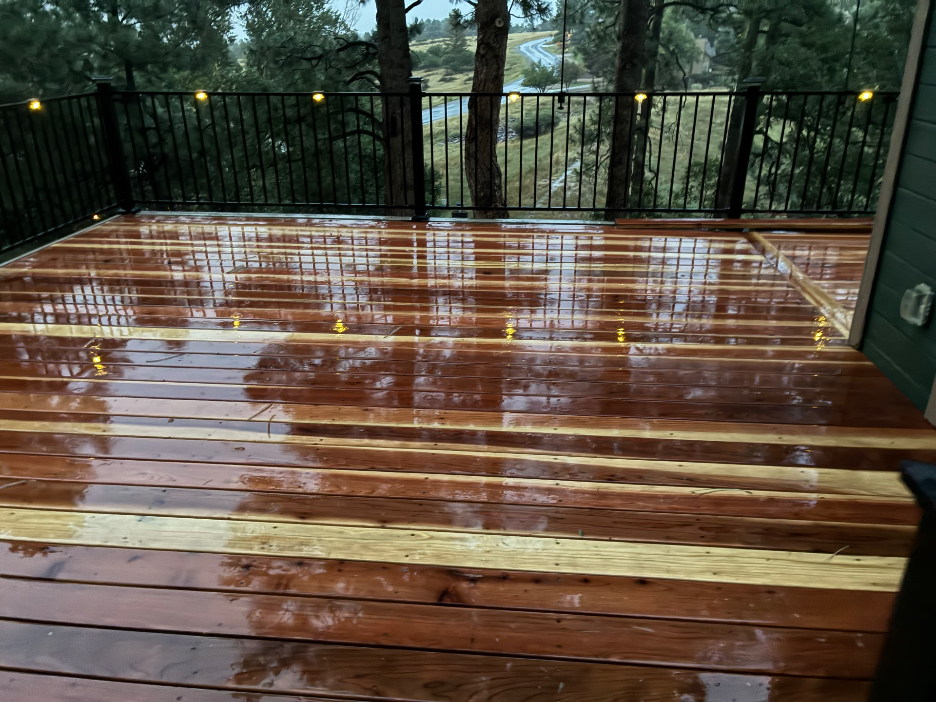 Freshly stained cedar deck with black railings and post lights at dusk